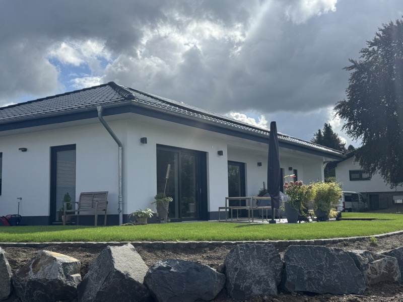 Gartenseite mit Terrasse, Sonnenschirm und Natursteinmauer in Flammersfeld